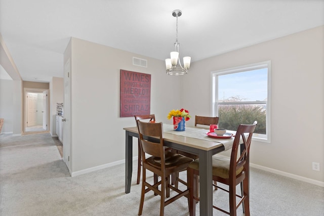 dining space featuring light carpet, baseboards, visible vents, and a chandelier