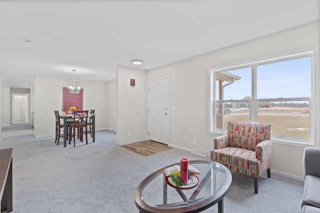 carpeted living room with baseboards, visible vents, and a chandelier