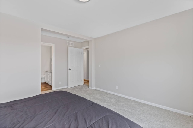 unfurnished bedroom with baseboards, visible vents, carpet flooring, and ensuite bathroom