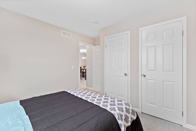 bedroom with light carpet, visible vents, and baseboards