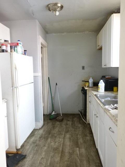 kitchen with freestanding refrigerator, white cabinets, light countertops, and a sink