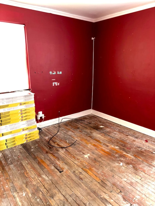 empty room featuring hardwood / wood-style floors, baseboards, and crown molding