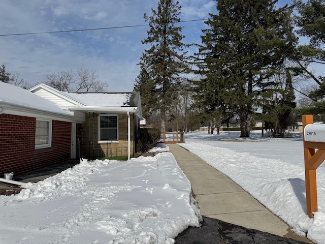 view of snowy exterior with stone siding