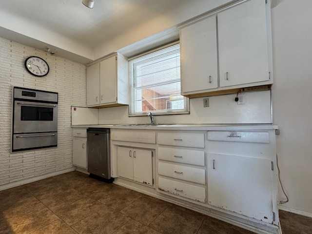 kitchen featuring a warming drawer, light countertops, stainless steel oven, and white cabinets