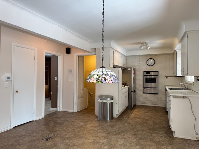 kitchen featuring light countertops, appliances with stainless steel finishes, hanging light fixtures, and white cabinetry