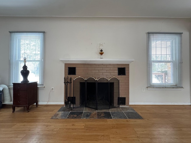 details with a fireplace, wood finished floors, visible vents, and baseboards