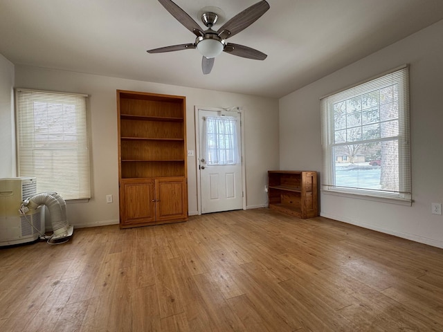 interior space featuring light wood-style floors, ceiling fan, baseboards, and built in features