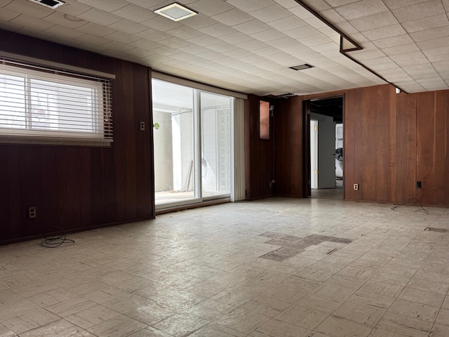 empty room with light floors, a wealth of natural light, and wooden walls