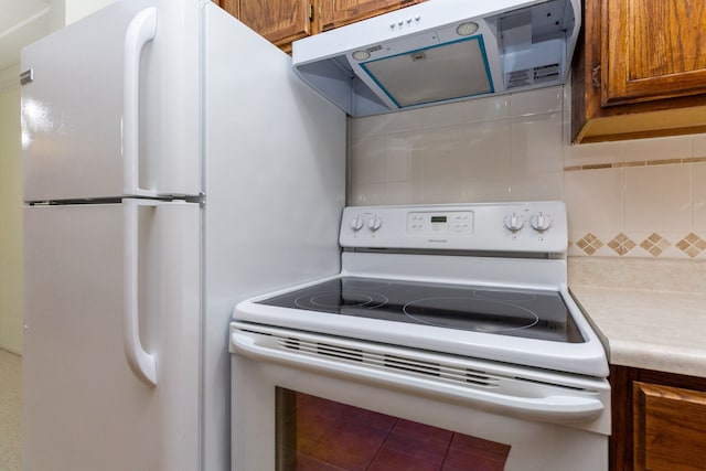 kitchen featuring brown cabinetry, range hood, white appliances, and light countertops