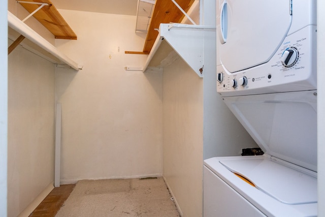 clothes washing area with laundry area, baseboards, and stacked washing maching and dryer