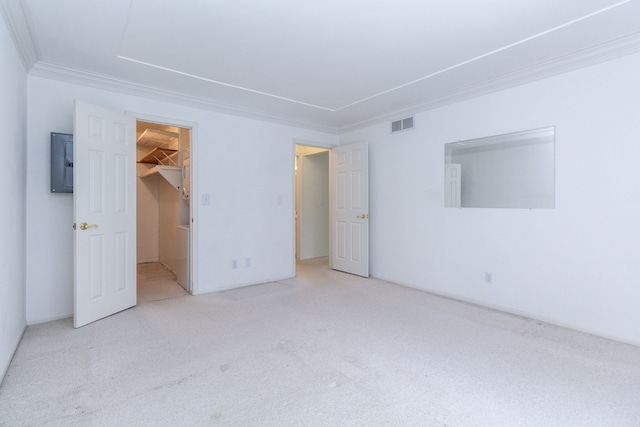 unfurnished bedroom featuring visible vents, light colored carpet, a walk in closet, crown molding, and a closet