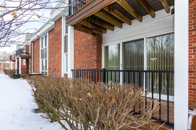 snow covered property with brick siding