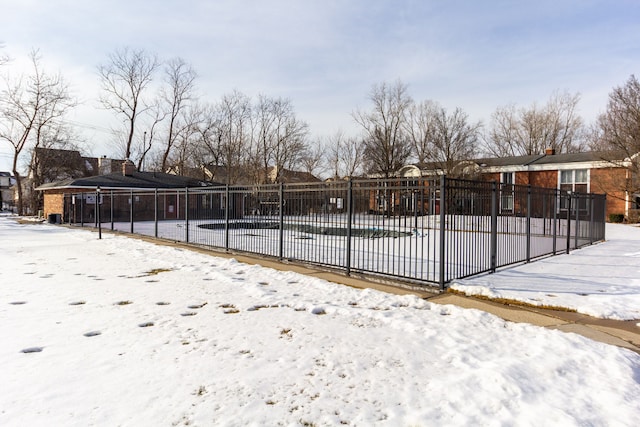 snow covered pool with a residential view and fence