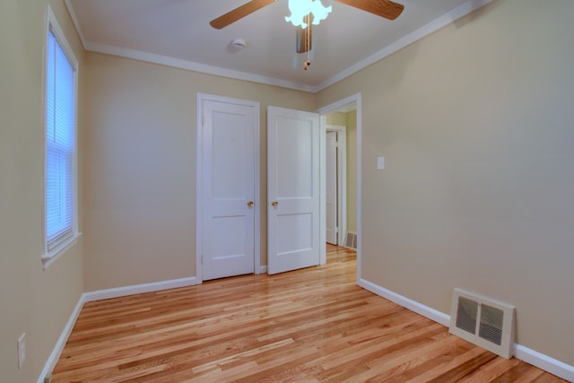 unfurnished bedroom with light wood-style floors, visible vents, and ornamental molding