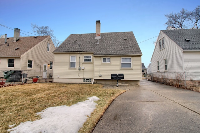 back of property featuring a yard, a chimney, fence, and roof with shingles