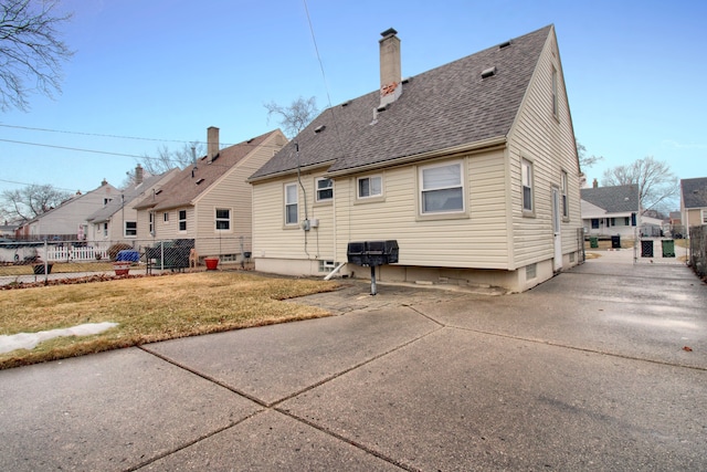 back of property featuring a yard, roof with shingles, a patio area, and fence