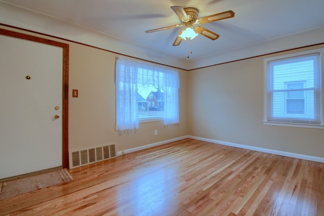 spare room featuring ceiling fan, wood finished floors, visible vents, and baseboards