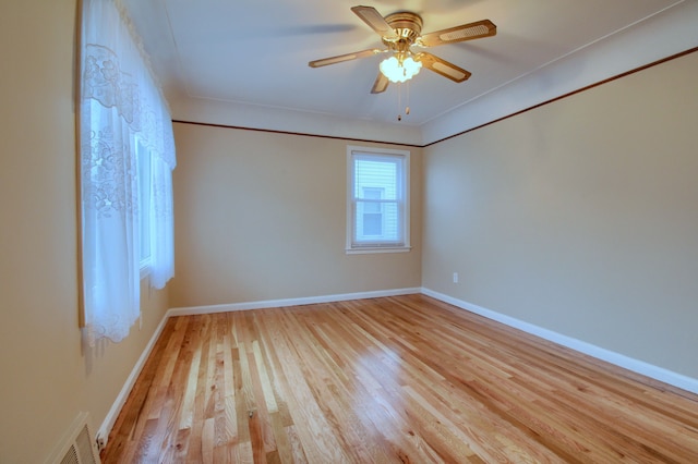 unfurnished room with crown molding, visible vents, light wood-style flooring, ceiling fan, and baseboards