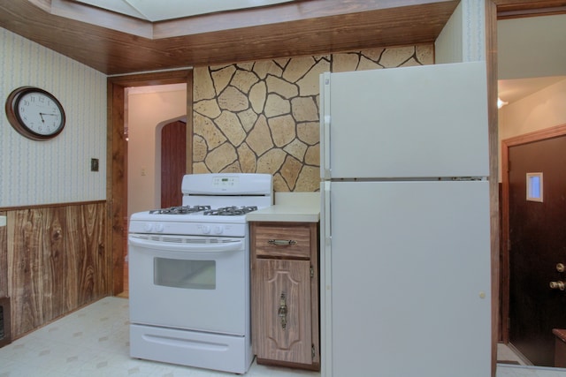 kitchen with light countertops, white appliances, a wainscoted wall, and wallpapered walls