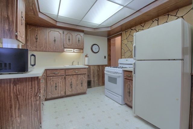 kitchen with white appliances, a sink, light countertops, light floors, and wallpapered walls