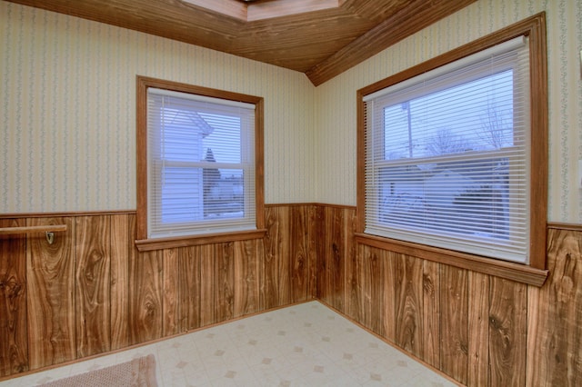 spare room with a wainscoted wall, wooden walls, wallpapered walls, and tile patterned floors