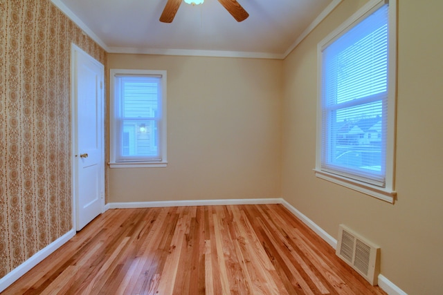 empty room featuring ornamental molding, plenty of natural light, visible vents, and baseboards