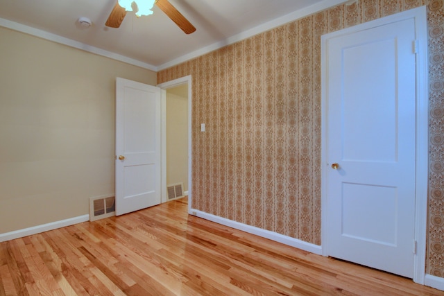 spare room featuring wallpapered walls, visible vents, and wood finished floors