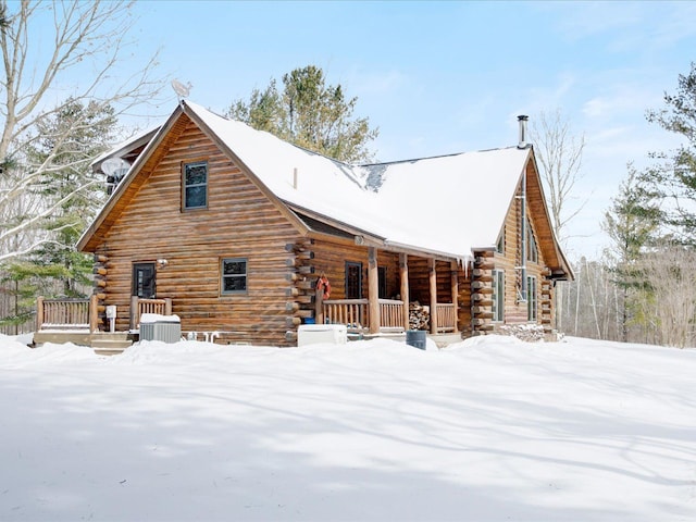 snow covered property featuring a porch, central AC, and log exterior