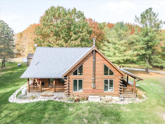 rear view of property featuring a porch, log siding, and a yard