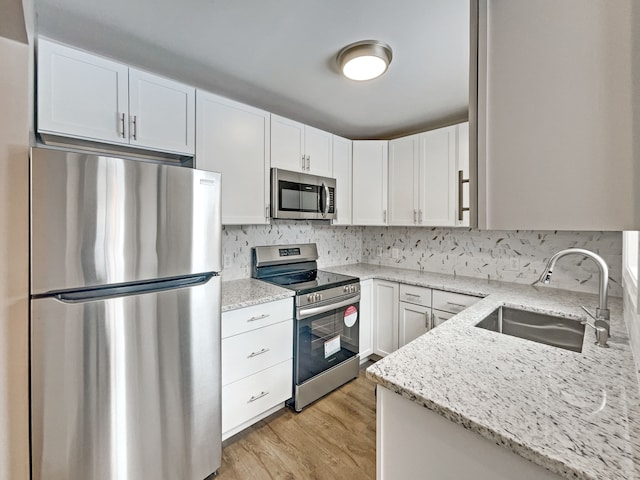 kitchen featuring stainless steel appliances, a sink, and light stone countertops