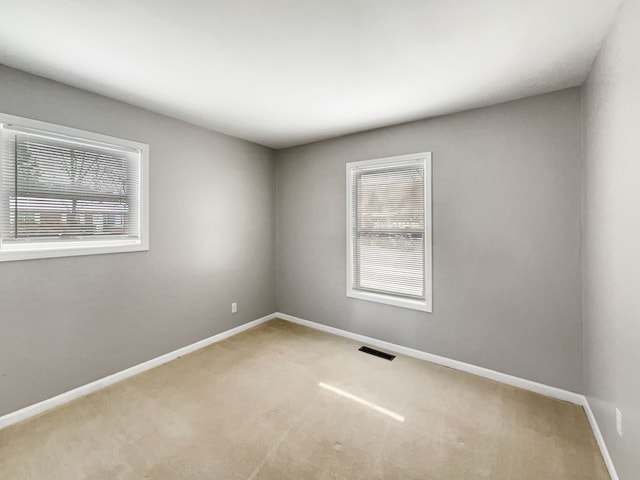 unfurnished room with carpet flooring, visible vents, and baseboards