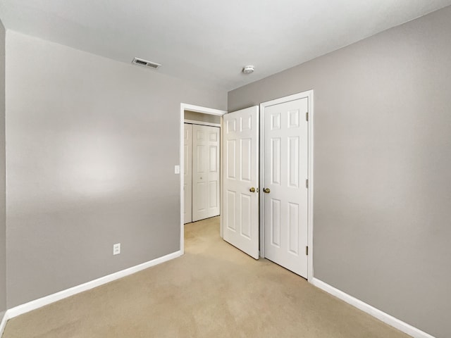 unfurnished bedroom featuring baseboards, visible vents, and light colored carpet