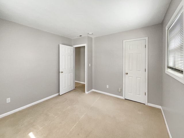 unfurnished bedroom featuring baseboards and light colored carpet