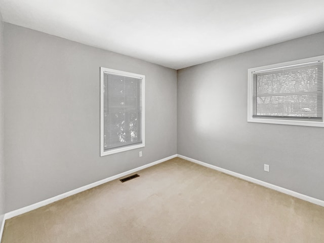 carpeted spare room featuring baseboards and visible vents