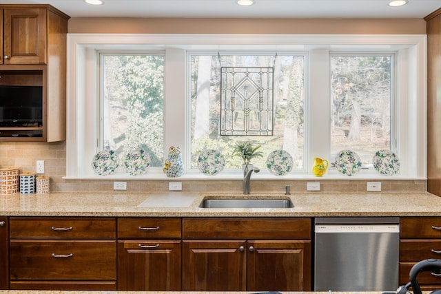 kitchen with light stone counters, recessed lighting, a sink, dishwasher, and tasteful backsplash