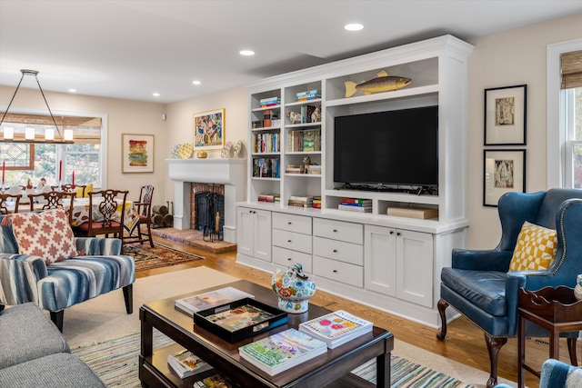 living room with a brick fireplace, wood finished floors, an inviting chandelier, and recessed lighting