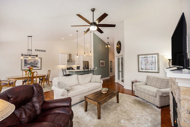 living room with light wood finished floors, baseboards, visible vents, high vaulted ceiling, and ceiling fan with notable chandelier