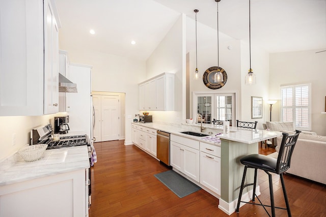 kitchen with appliances with stainless steel finishes, open floor plan, white cabinetry, light stone countertops, and a kitchen breakfast bar