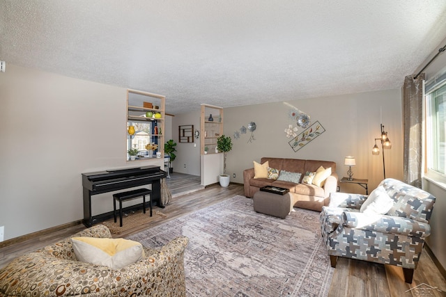 living area with a textured ceiling, baseboards, and wood finished floors