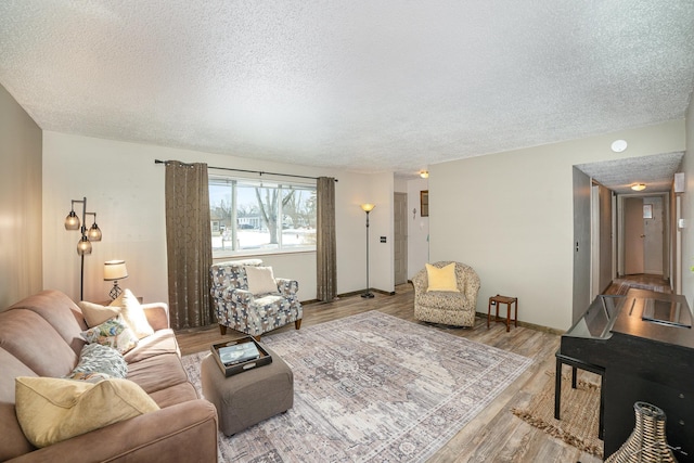 living room featuring a textured ceiling, light wood finished floors, and baseboards