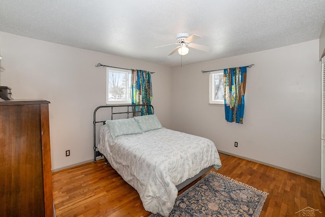 bedroom featuring a textured ceiling, ceiling fan, wood finished floors, and baseboards