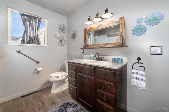 full bathroom with visible vents, toilet, vanity, wood finished floors, and baseboards