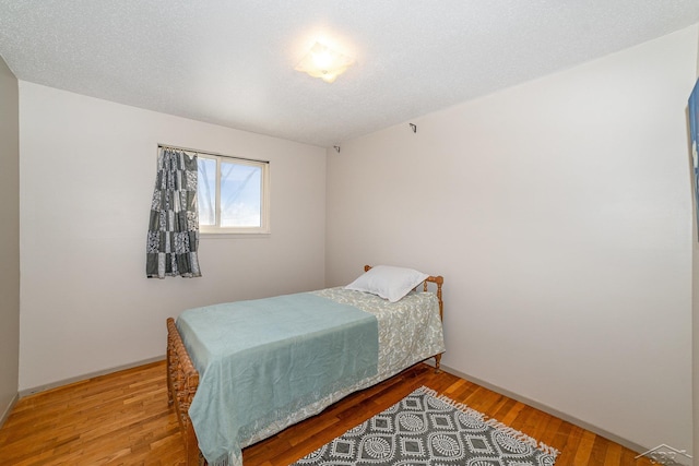 bedroom with a textured ceiling and wood finished floors