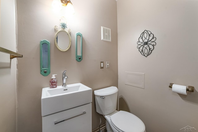 half bathroom with visible vents, vanity, and toilet