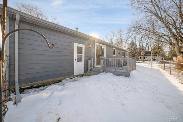 snow covered house featuring fence