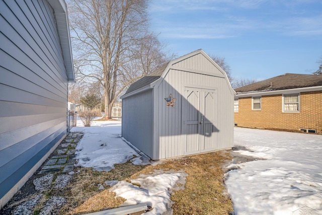 snow covered structure with an outbuilding and a shed