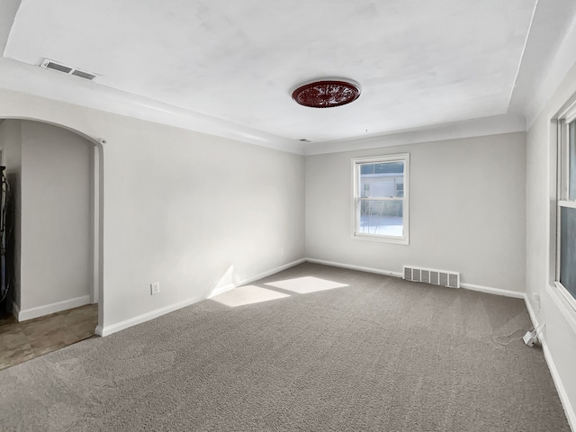 unfurnished room with carpet, visible vents, and arched walkways