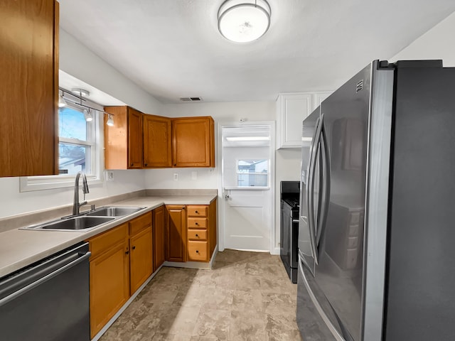 kitchen featuring a sink, visible vents, light countertops, black appliances, and brown cabinetry