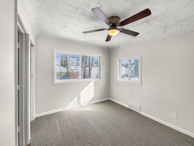 unfurnished bedroom featuring carpet, visible vents, a ceiling fan, a textured ceiling, and baseboards