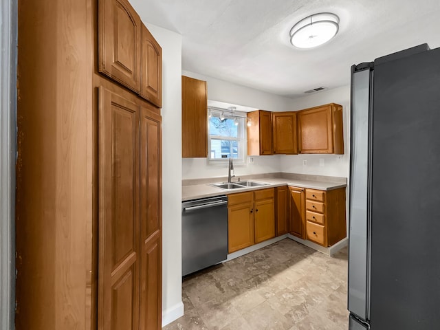 kitchen with brown cabinets, stainless steel appliances, light countertops, visible vents, and a sink